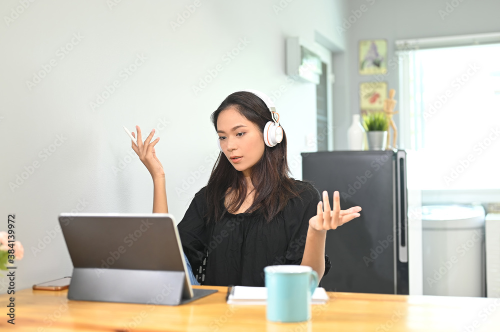 Young female using tablet for video calling with her colleague at home. Young female using tablet for video calling with her colleague at home.