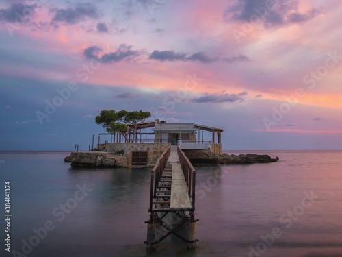Camp De Mar sunset, wooden boardwalk leading to restaurant on an island with colouful sky and calm sea, Mallorca, Spain.