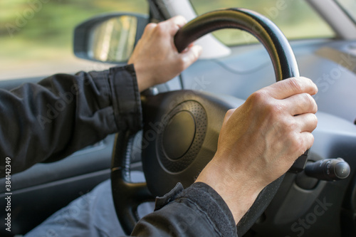 male hands on the steering wheel, driving a car. The concept is learning to drive, driving safely, traveling by car. soft, selective focus, horizontal photo.