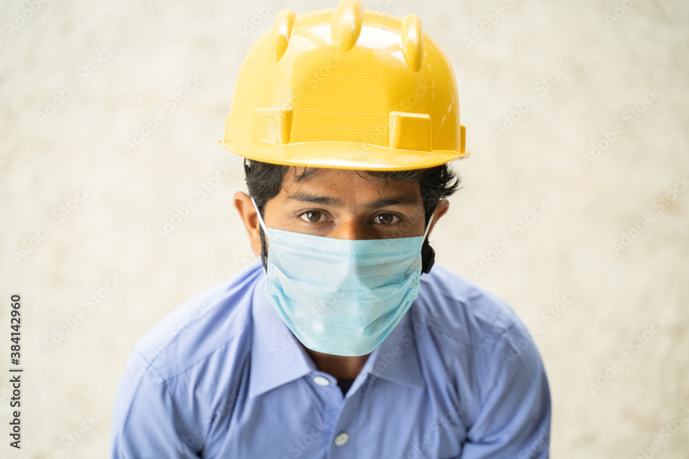 Hing angle view of Construction worker in medical mask looking up in confident - concept of business, industry reopen and covid-19 safety measures at workplace. Hing angle view of Construction worker in medical mask looking up in confident - concept of business, industry reopen and covid-19 safety measures at workplace.
