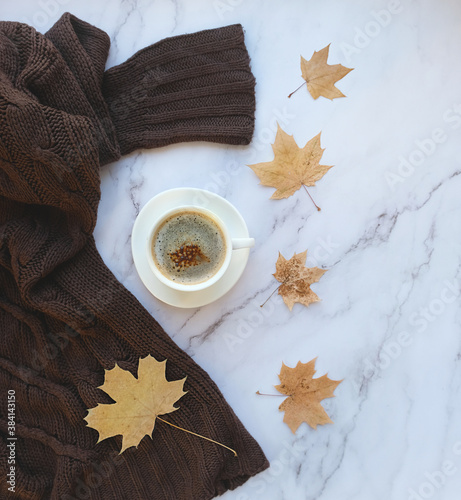 autumn leaves, coffee cup , knitted sweater on marble background. cozy autumn composition. fall, thanksgiving day concept. Flat lay, top view. copy space