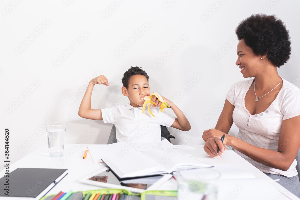 Fototapeta premium Mother with strong son eating banana while studying at home