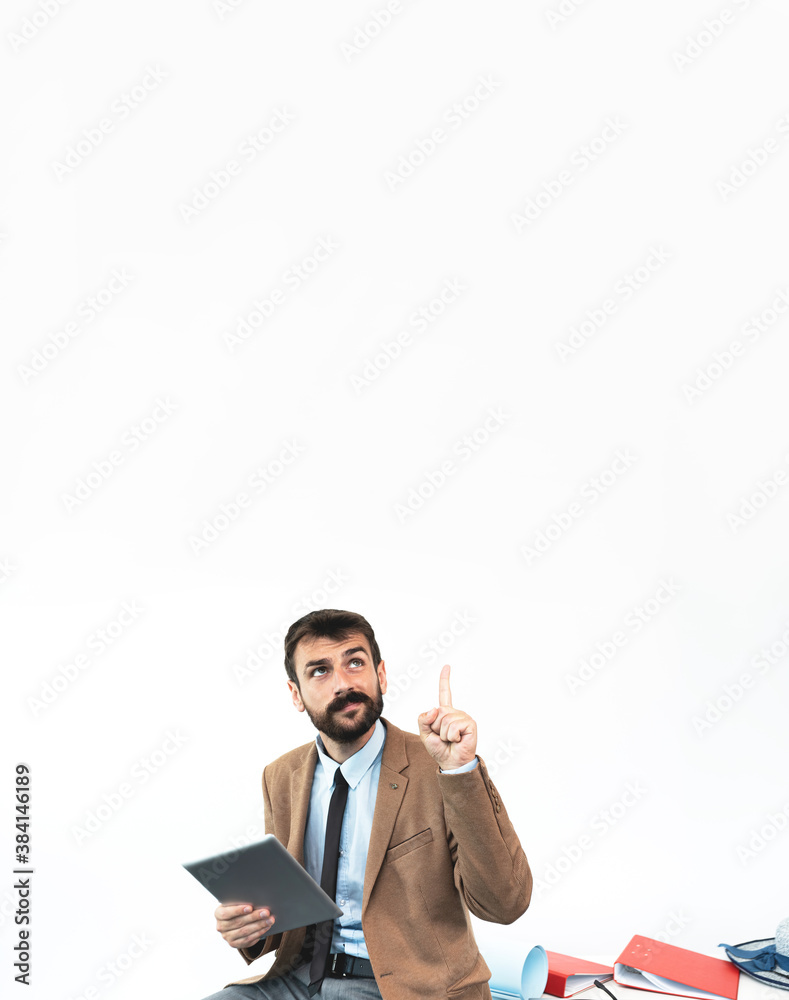 Upset businessman holding digital tablet while pointing finger and looking up