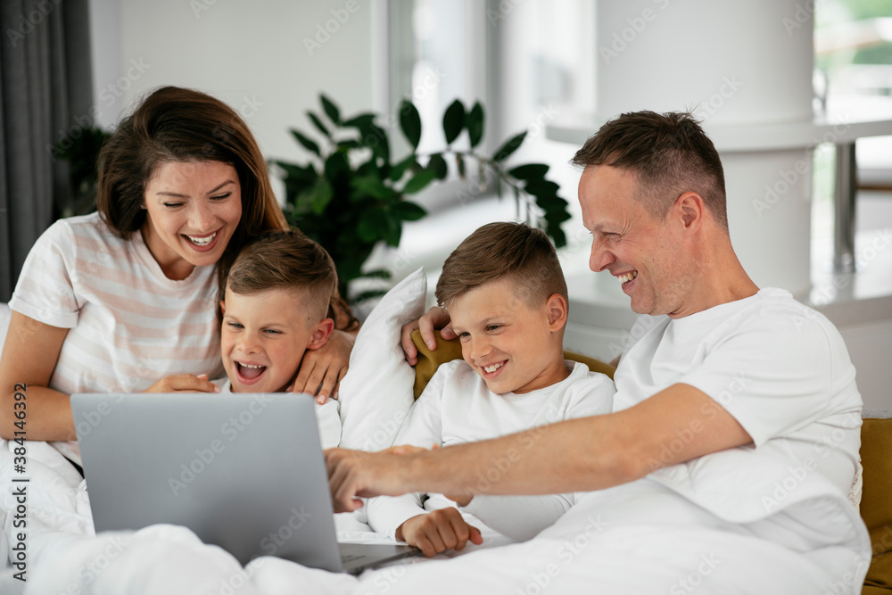 Beautiful parents with kids enjoying at home. Young family watching movie on lap top Beautiful parents with kids enjoying at home. Young family watching movie on lap top