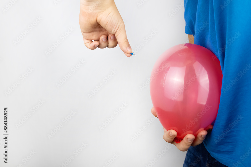 Conceptual photography. The man holds a red ball near his belly, which symbolizes bloating and flatulence. Then he brings a needle to it to burst the balloon and thus get rid of the problem. Conceptual photography. The man holds a red ball near his belly, which symbolizes bloating and flatulence. Then he brings a needle to it to burst the balloon and thus get rid of the problem.