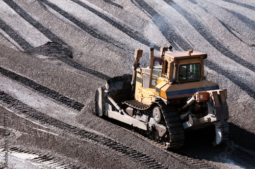 The bulldozer harrows the mountain soil, and then removes the top layer with an industrial bucket. Extraction of minerals in mountainous areas, in Siberia (gold mining)