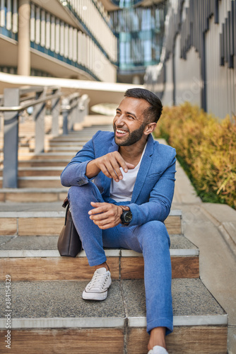 Casual smiling Indian arabic business man sitting on stairs