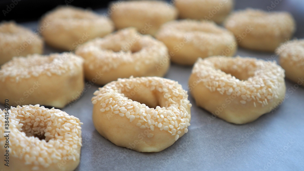 Close-up sesame seeds stuck to the dough, tiny bagels with sesame seeds,