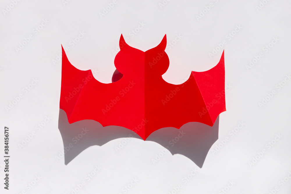 Halloween holiday background red paper bat with hard shadow on white background. Creative minimalism style greeting card Halloween holiday background red paper bat with hard shadow on white background. Creative minimalism style greeting card