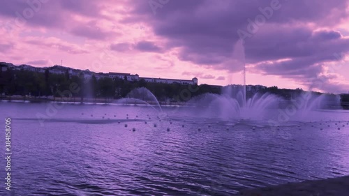 Mondego river sunset with purple light and an ornamental fountain with moving water in Coimbra