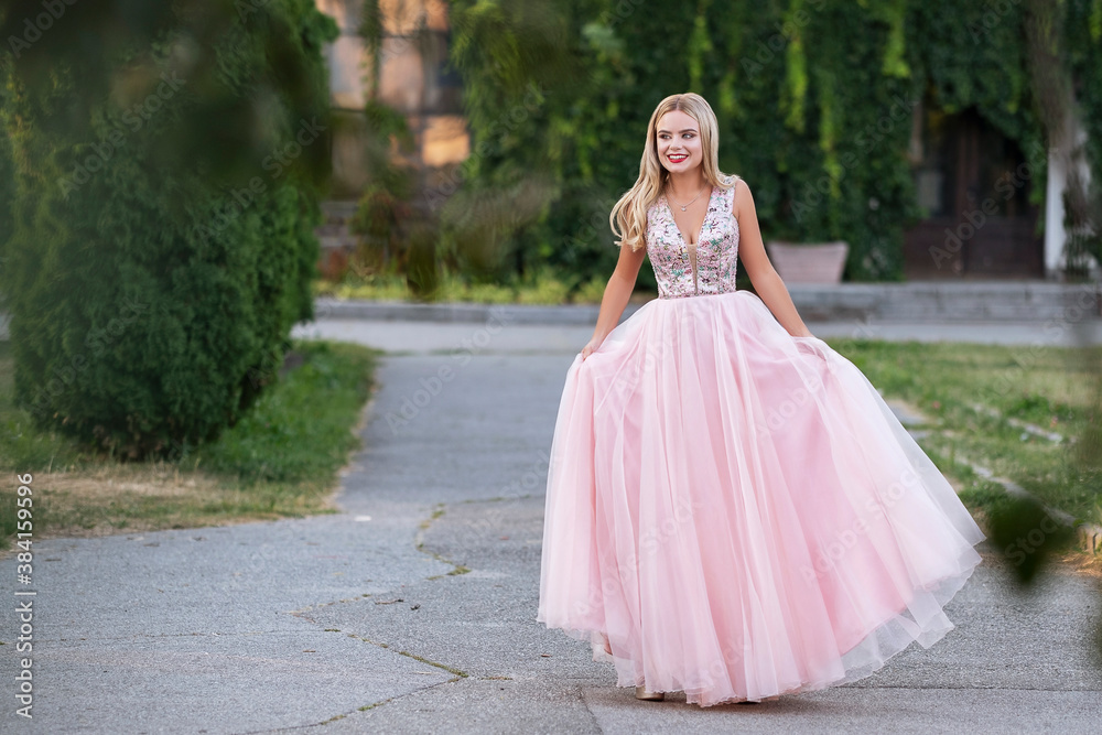 Blonde woman with make up in evening dress at park. The skirt of her dress fly on a wind. Sensual fashion portrait with a sunset light Blonde woman with make up in evening dress at park. The skirt of her dress fly on a wind. Sensual fashion portrait with a sunset light