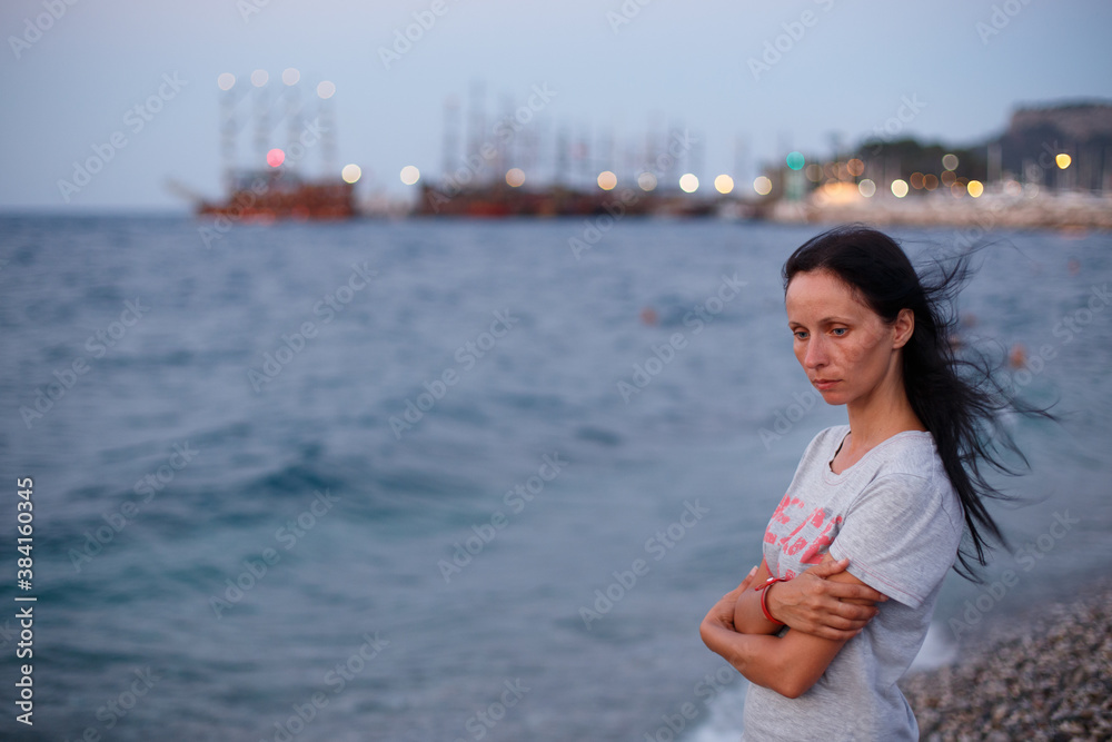 sad woman standing on the beach with long hair