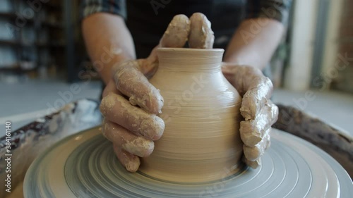 Seamless loop of hand-made ceramic pot spinning on potter's wheel in craftsman's hands. Traditional occupation and leisure time activities concept.
