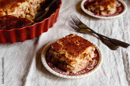 Apple and Cheese Cobbler Crisp. Cobbler or Crumble dessert with apples in ceramic baking form on beige linen table. Selective focus photo