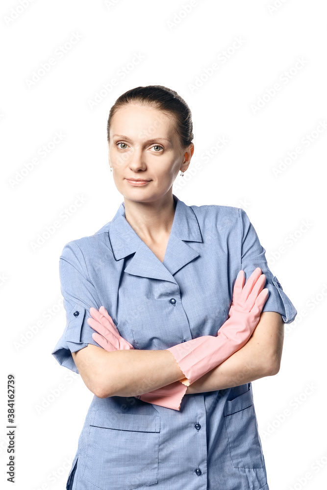 A beautiful young woman in the uniform of a maid smiling crossed her hands in rubber gloves on her chest. Isolated on a white background.