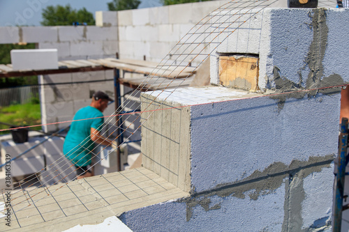 A worker builds the walls of a house from aerated concrete bricks.