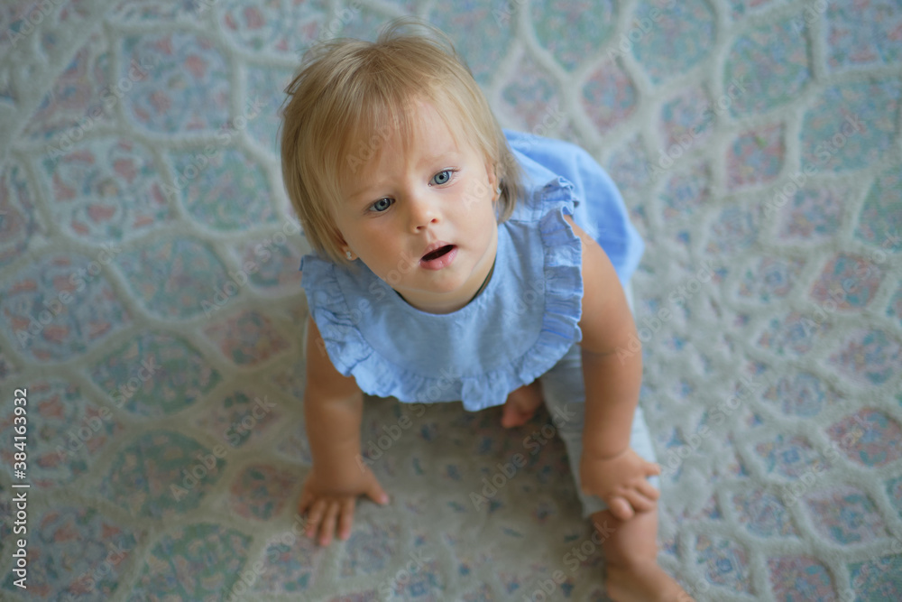 Naklejka premium childhood, babyhood and people concept. happy little baby girl sitting on floor at home. view from above