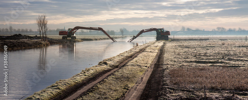 Dredging of an inland canal by cranes in winter at sunset.  photo