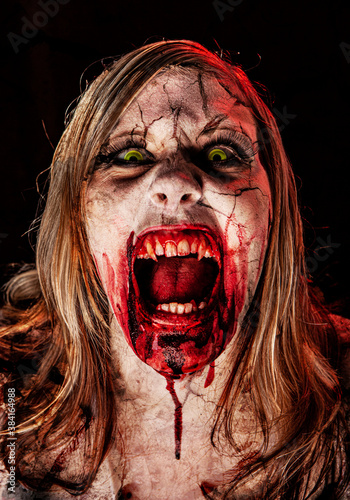 Studio portrait of a female vampire of zombie with open mouth, screaming and looking at camera