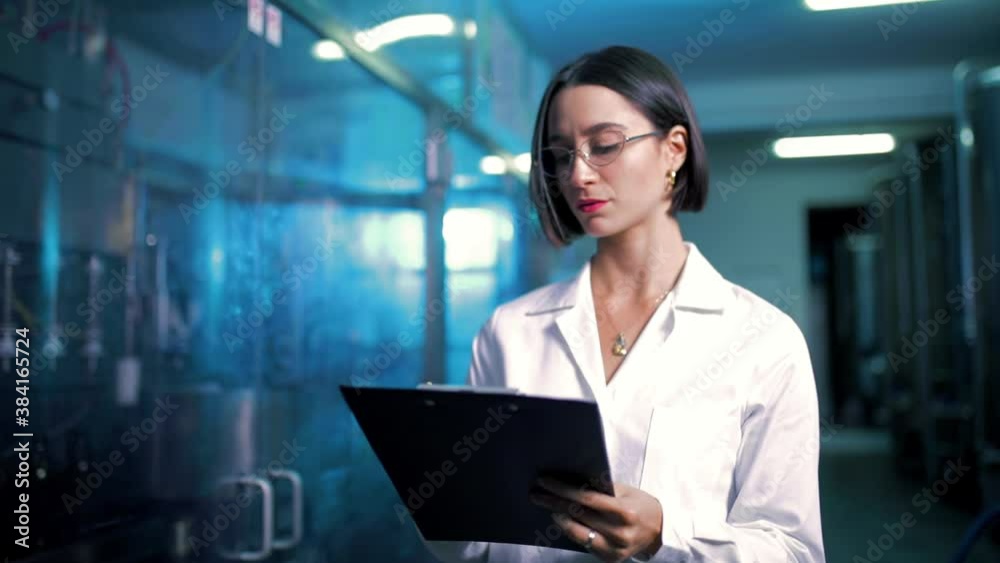 Ragazza chimico del controllo qualità sta guardando la produzione di bottiglie nella fabbrica