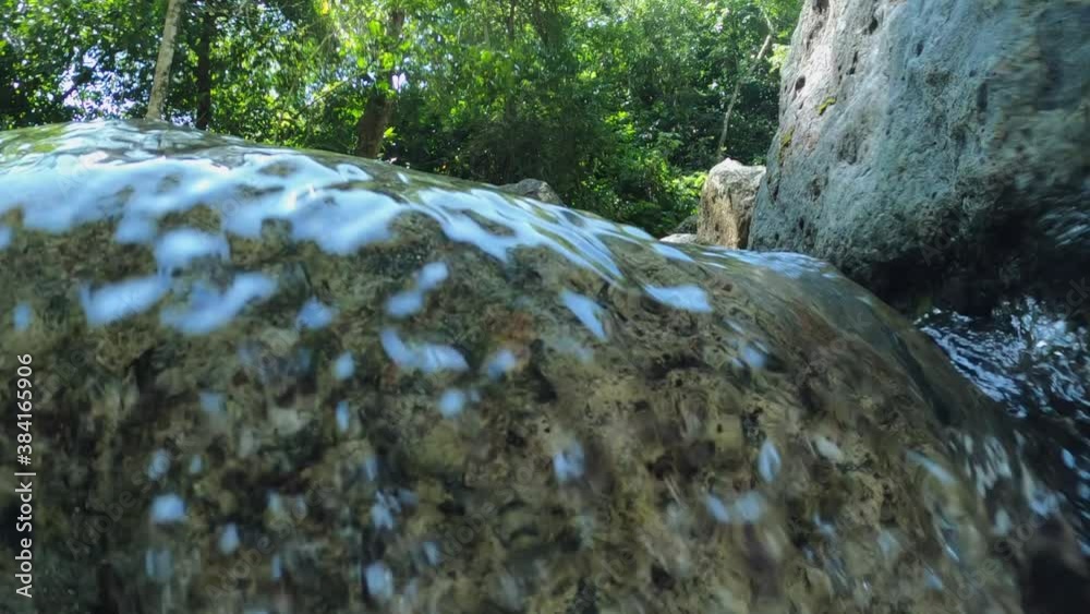 Cinematic shot of waterfall water flow as camera goes underwater. Slow motion