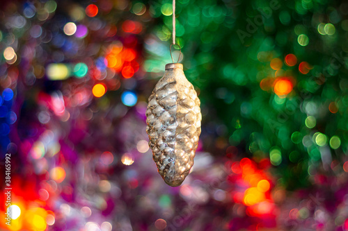 An old vintage Soviet Christmas tree toy cone on a background of multicolored tinsel and a glowing garland.