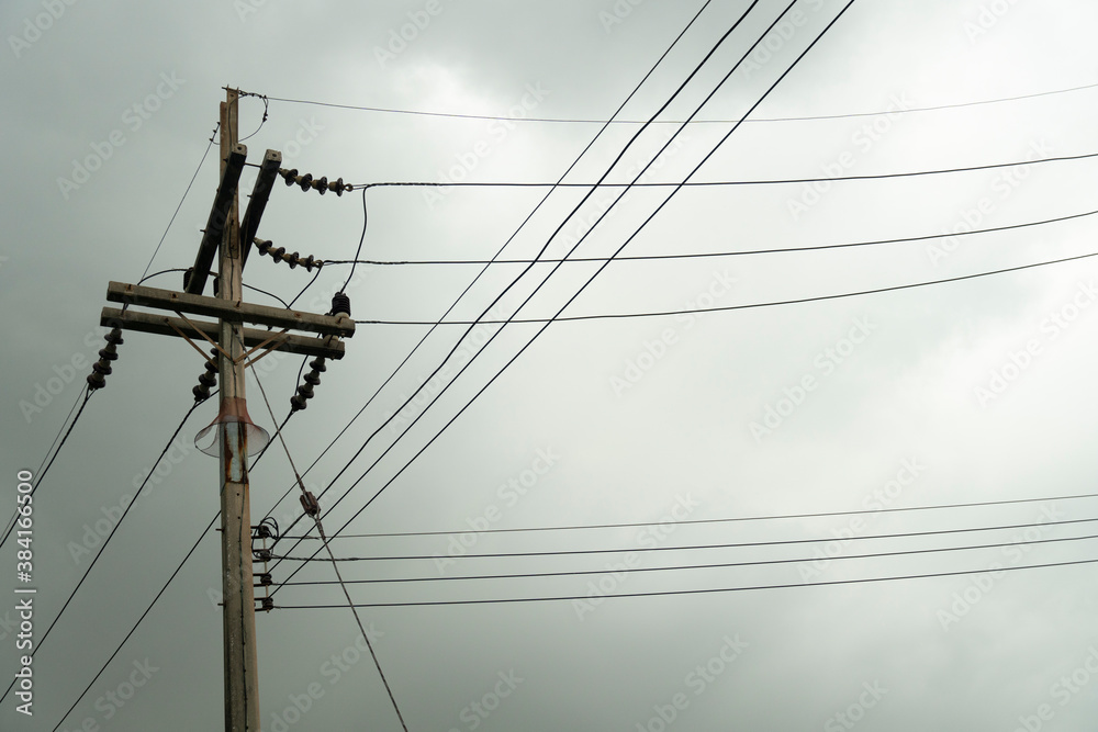 Fototapeta premium Electric pole with many cable under dark clouds before rainy.