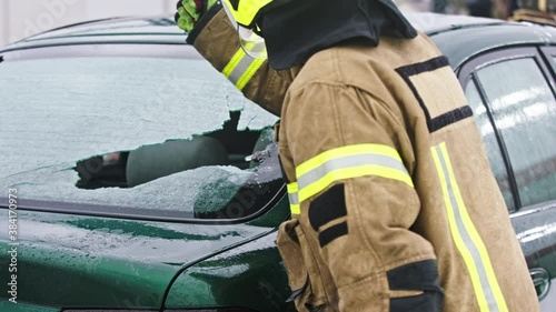 Firefighter beraking glass on car window extricate trapped victim from the car. High quality 4k footage photo