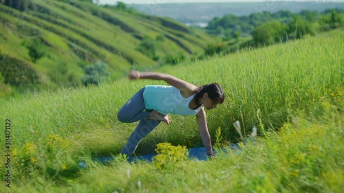 Young woman doing yoga in green summer meadow