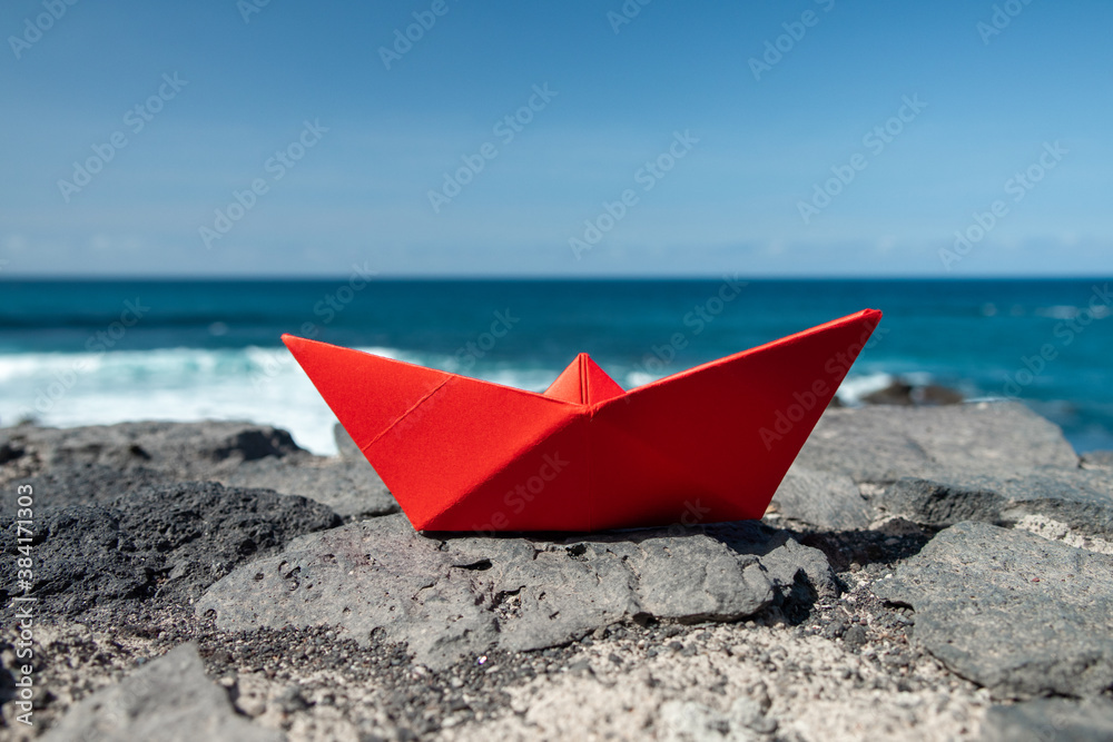 Red paper boat in front of the ocean outdoors Red paper boat in front of the ocean outdoors