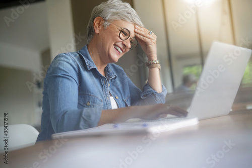 portrait of a beautiful 55 year old woman with white hair working from home