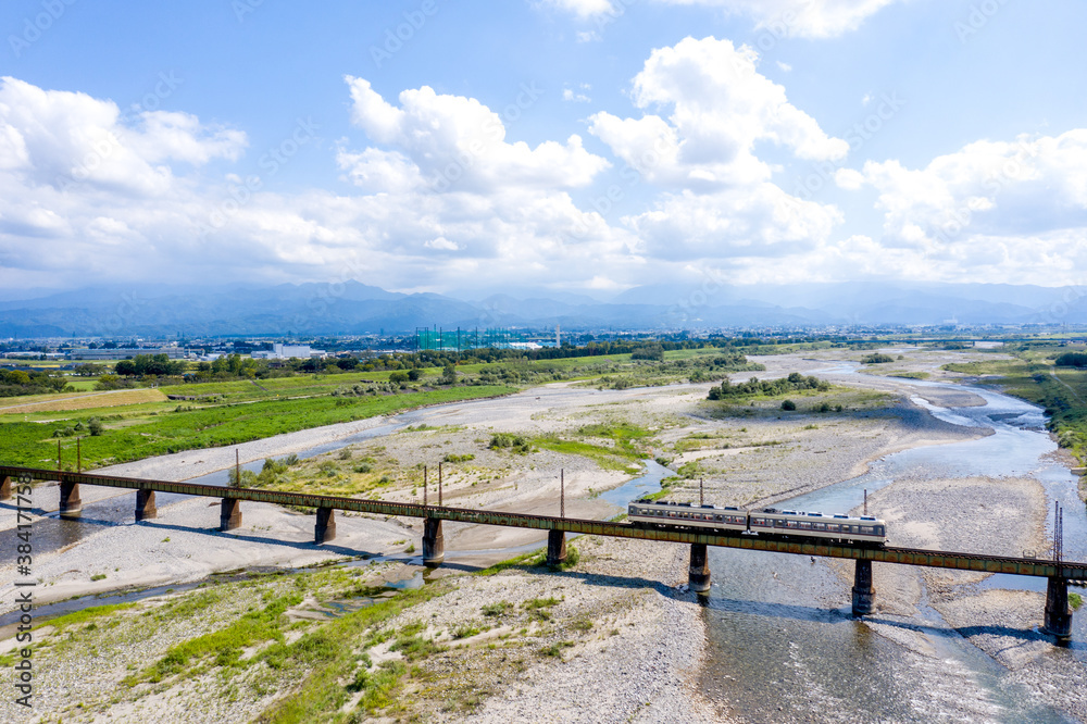 北アルプスを背景に常願寺川を渡る富山地方鉄道本線の普通列車