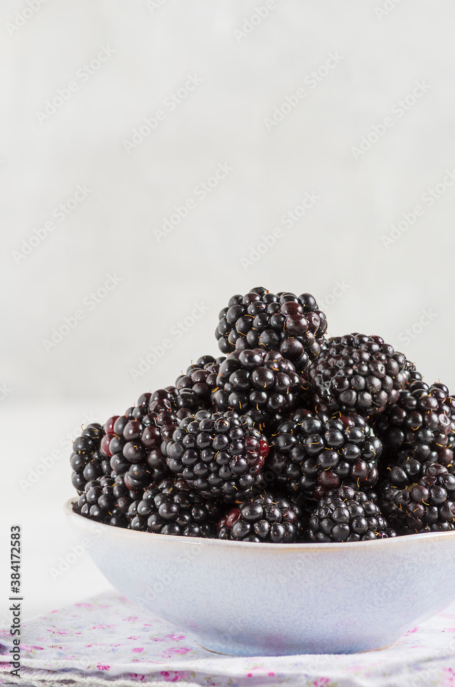 Bowl with ripe blackberries on a delicate grey surface. Macro photo of ripe blackberries. Bowl with ripe blackberries on a delicate grey surface. Macro photo of ripe blackberries.