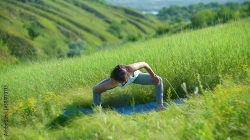 Young woman doing yoga in green summer meadow