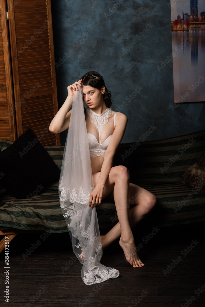 Beautiful bride in white lingerie sitting in her bedroom and studio.