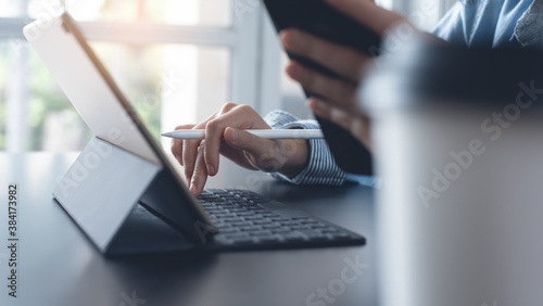 Business woman hands using mobile phone while working on digital tablet and laptop computer
