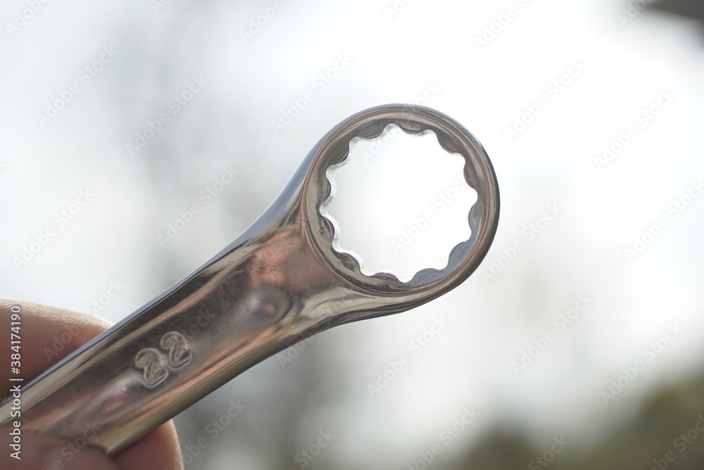 hand with wrench on sky background