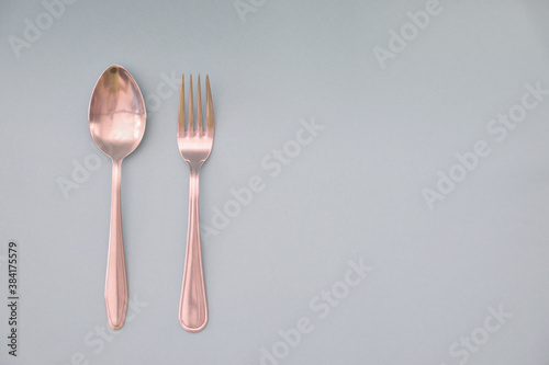 A tablespoon and fork are laid out in parallel and isolated on a light background.