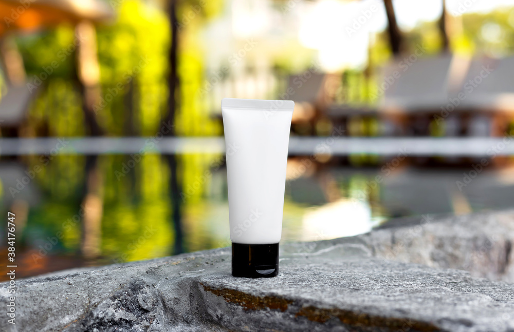 White empty tube of cream on blurred leaves and water background. Skin care bottle, sun screen, gel, hand cream on stone pool border. Mock up. Packaging design. Sun protection cosmetics. Moisturizer