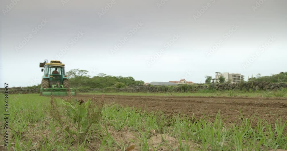 Tractor ploughing field, Jeju do, South Korea Tractor ploughing field, Jeju do, South Korea