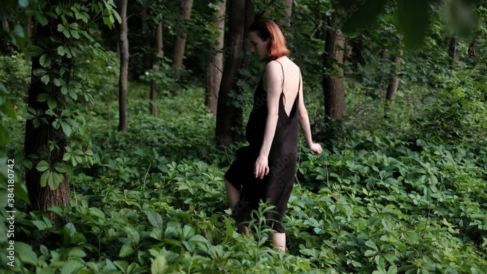 Young women slowly walking barefoot through the forest wearing beautiful black slip dresses Young women slowly walking barefoot through the forest wearing beautiful black slip dresses