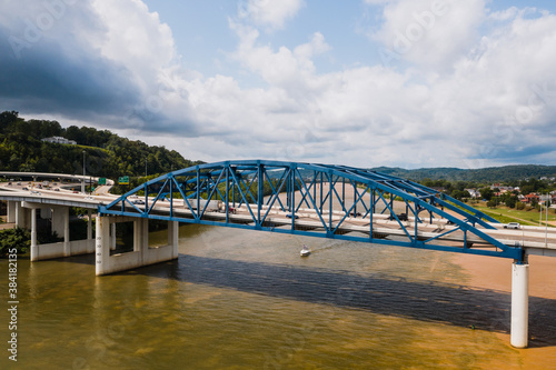 This is an aerial of a blue, eight-lane highway arch bridge that carries Interstate 64 over the Kanawha River in Charleston, West Virginia.