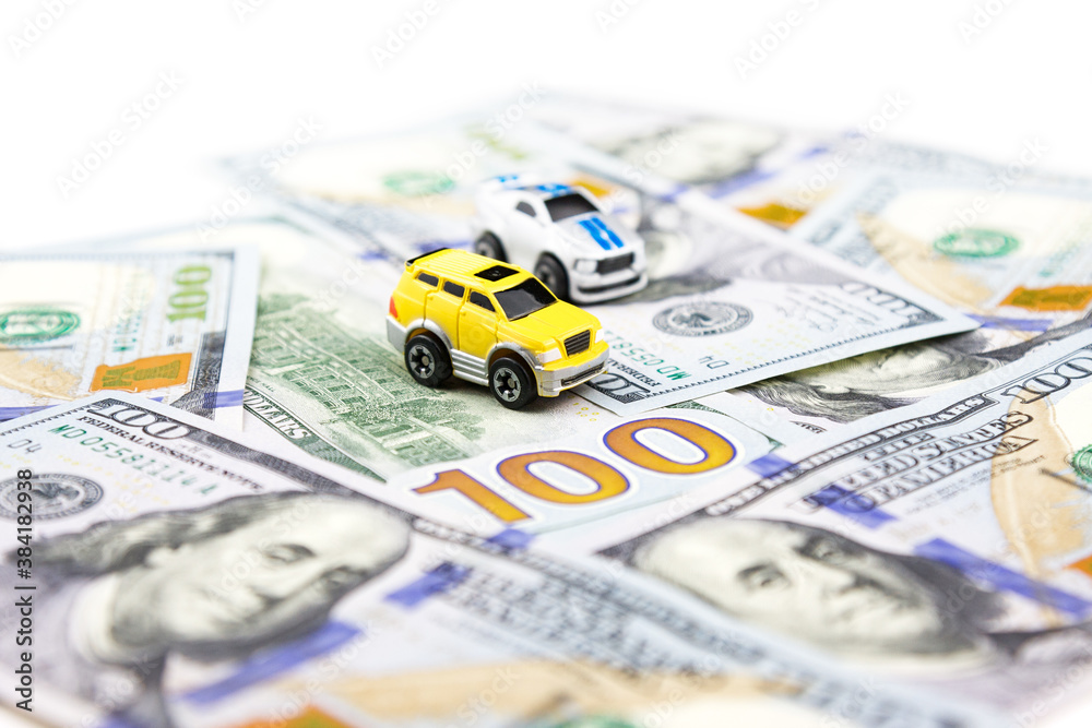Two toy cars on dollars. Car purchase and insurance. Car rental, repair, maintenance. Business in automobile industry