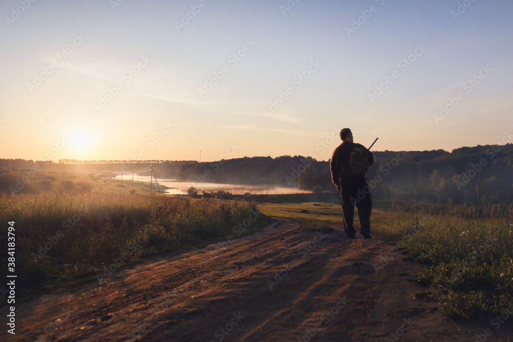 a man walks illuminated by the morning sun on the way to the forest a man walks illuminated by the morning sun on the way to the forest