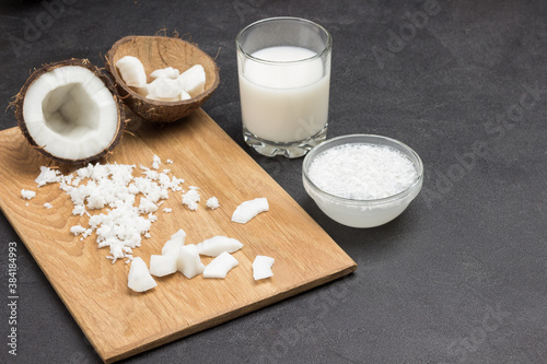 Pieces of coconut and half of coconut on board.