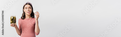 Photography panoramic crop of pregnant woman eating cupcake and holding jar with pickled cuc