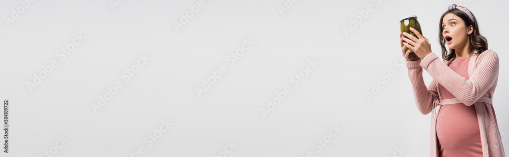 panoramic crop of shocked and pregnant woman holding jar with pickled cucumbers isolated on white panoramic crop of shocked and pregnant woman holding jar with pickled cucumbers isolated on white