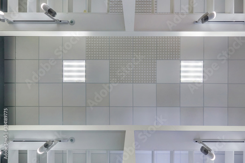 cassette suspended ceiling with square halogen spots lamps and drywall construction in empty room in apartment or house. Stretch ceiling white and complex shape. Looking up view