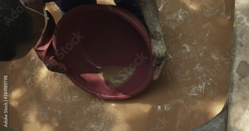 Man searching for metal in dirty water, Busia, Busitema, Kenya photo