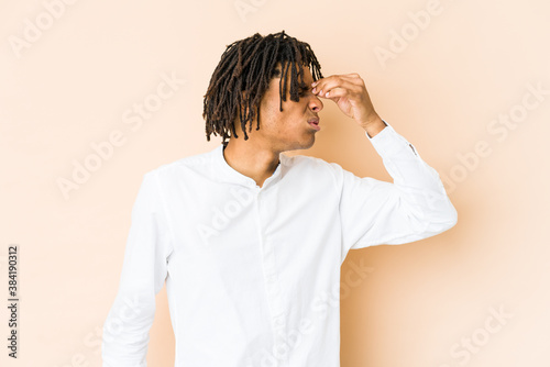 Young african american rasta man having a head ache, touching front of the face.